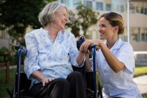 A group of older adults sharing a conversation and laughter around a common table in a bright, welcoming room.