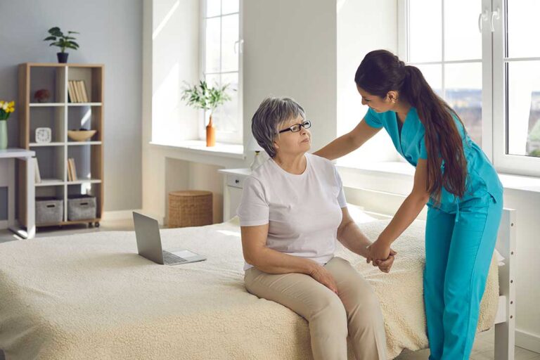 Family members arrange labeled clothing, toiletries, photos, and mobility items in an assisted living room.